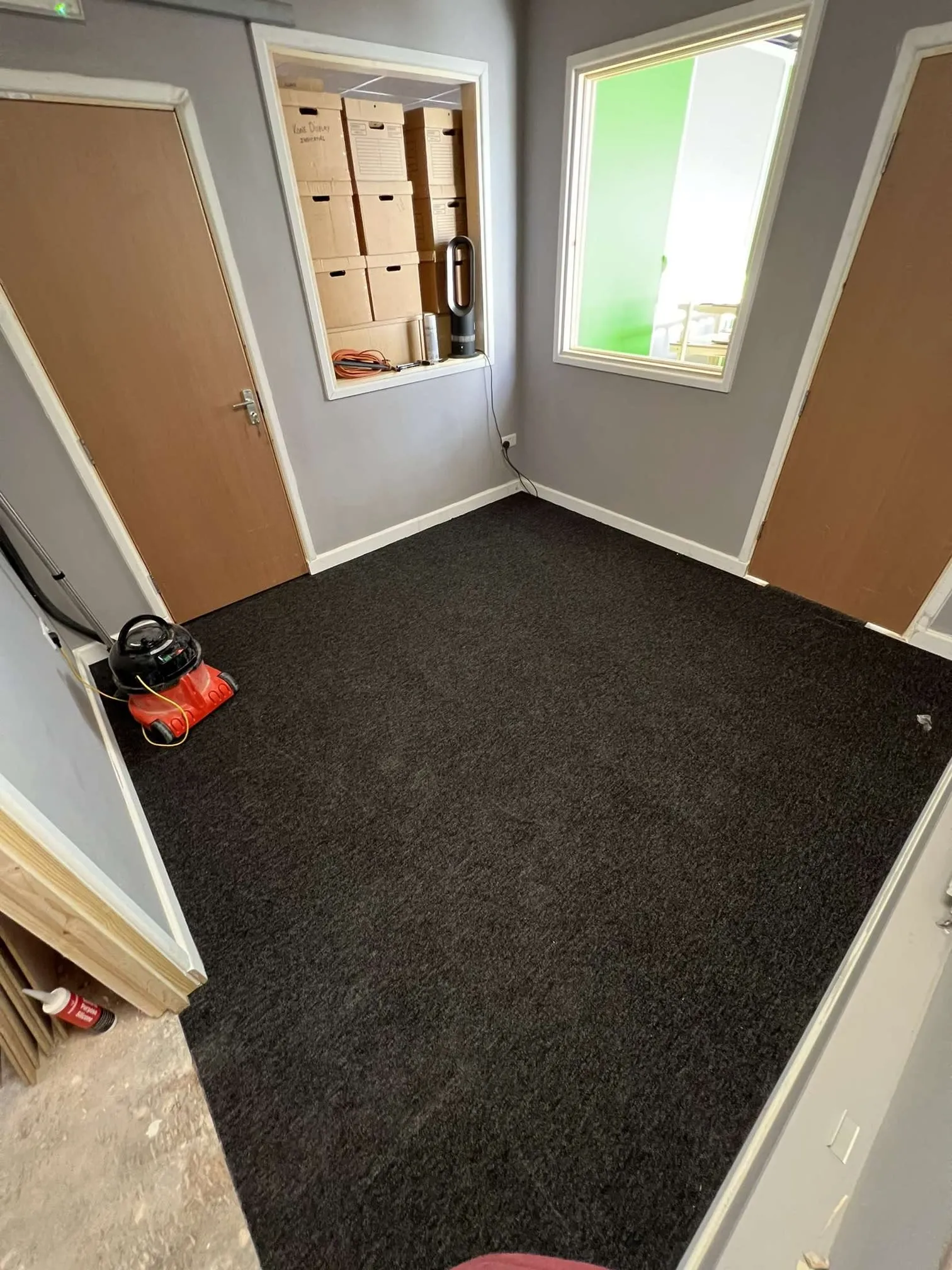 A room with a black carpet and a red chair.